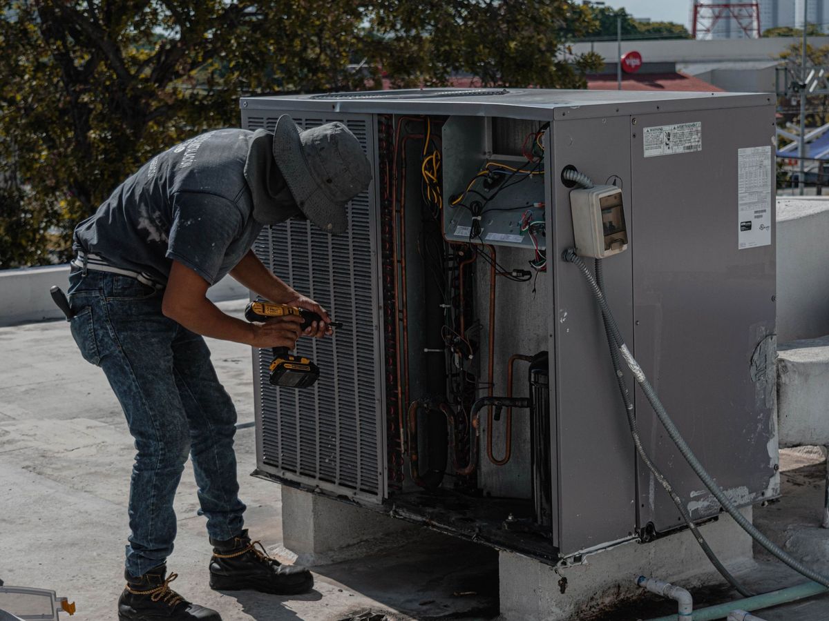 HVAC technician repairing an open rooftop package unit, heating and air service in Central Arkansas